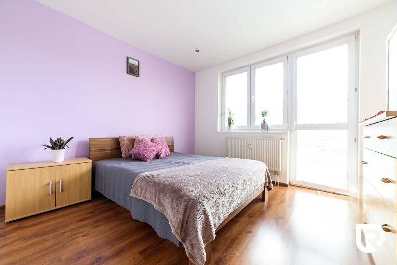Bedroom in a 2-room apartment with a bed, wardrobe, and wooden decor flooring.