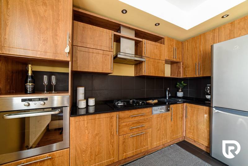 A kitchen in a 2-room apartment with a wooden decor and stainless steel appliances.