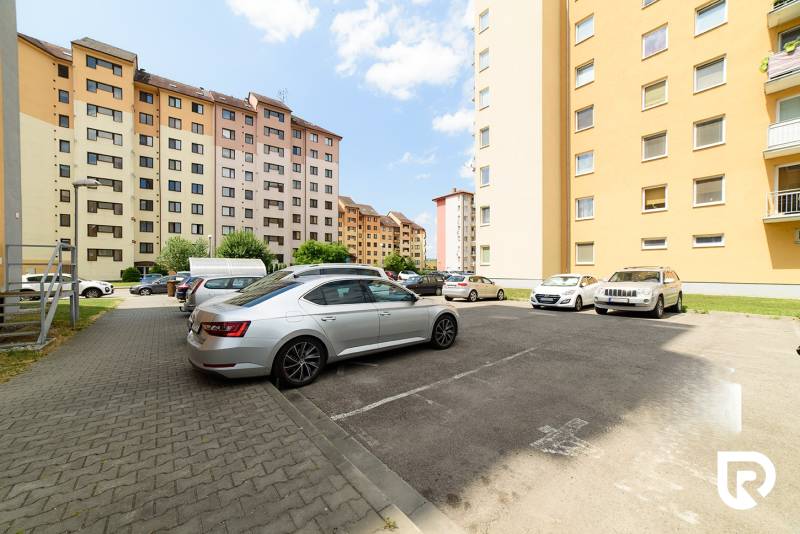 Parking lot on Armádna Street in Trenčín with parked cars in front of apartment buildings.