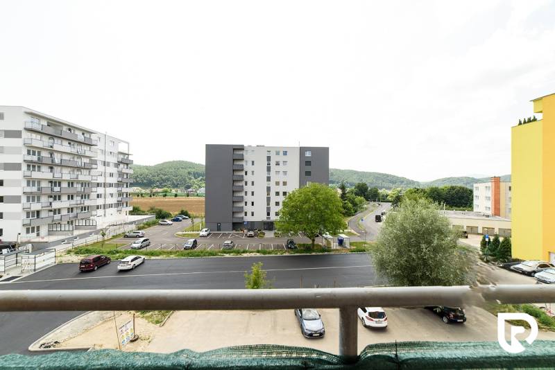 The view from the balcony on Armádna Street in Trenčín, surrounded by greenery and buildings.