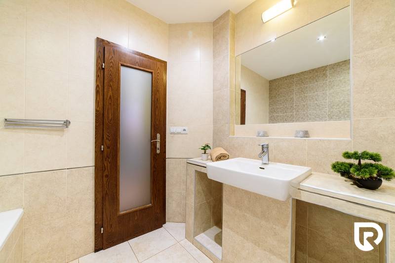Bathroom in a 2-room apartment with beige tiles and a plant on the shelf.