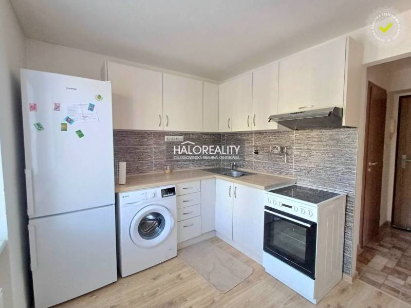 A kitchen in a studio apartment with white cabinets and a wood-patterned floor.