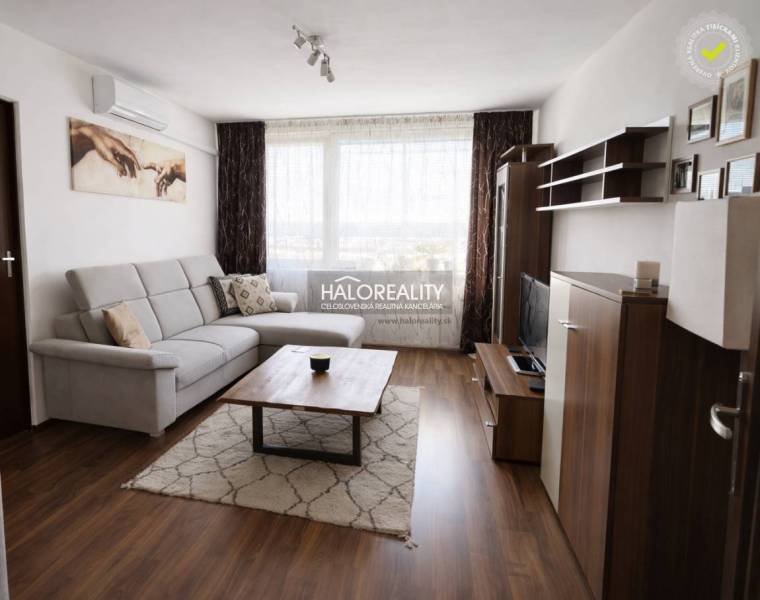 Living room in a 4-room apartment with a wooden decor floor, a sofa, and a television.