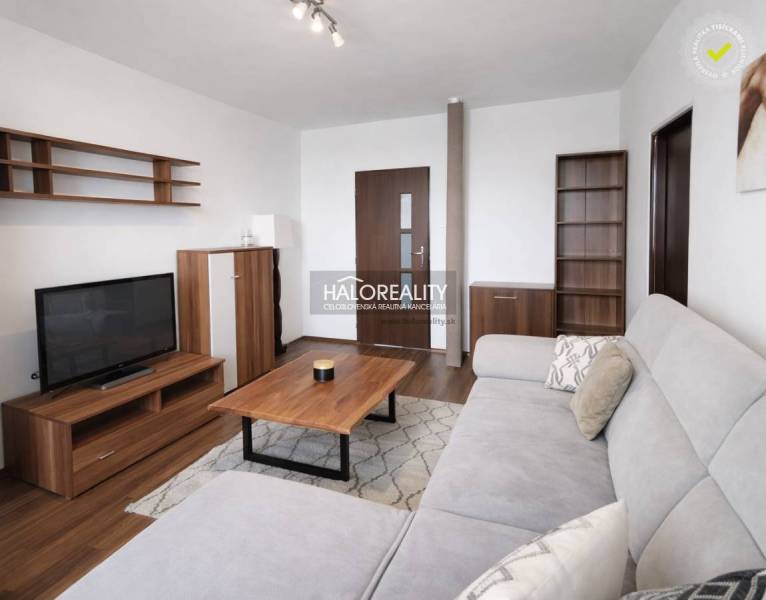 Living room with wood-patterned flooring, a sofa, and a television in a four-room apartment.