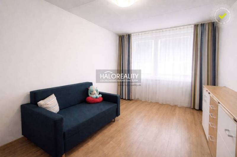 A room in a 4-room apartment with a blue sofa and a wooden decor floor.