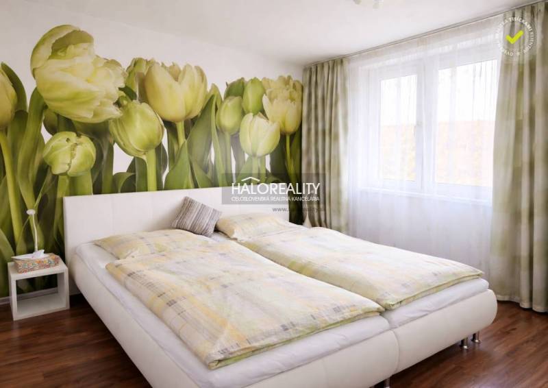 Bedroom in a 4-room apartment with tulip wallpaper and a floor bed with a wooden decor.