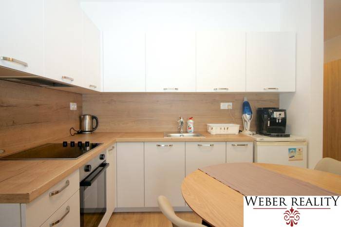 White kitchen with wood decor in a studio apartment with appliances.