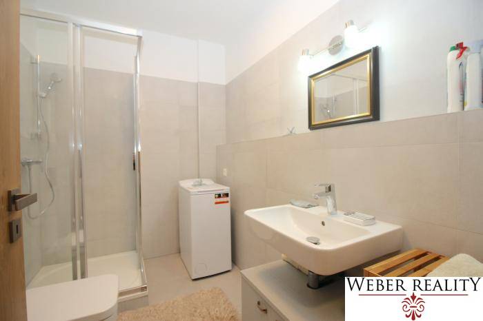 Bathroom with a sink, washing machine, and shower in a studio apartment.