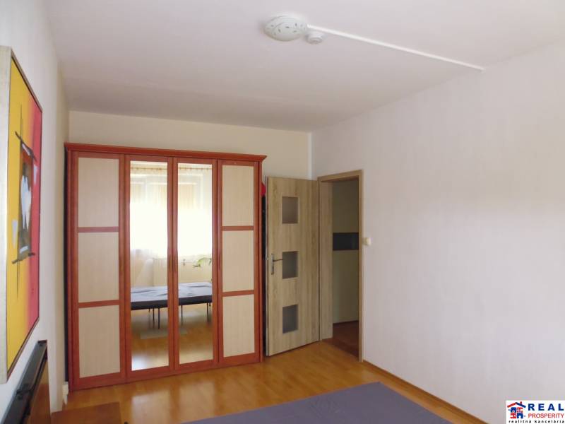 Interior of a 2-room apartment with a large mirrored wardrobe and a floor with a wooden decor.