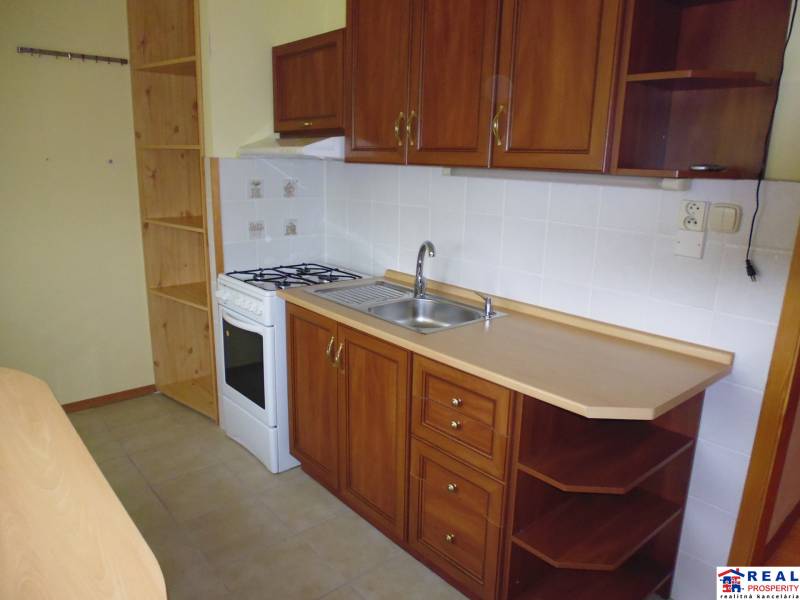 A kitchen in a 2-room apartment with cabinets and white tiles.