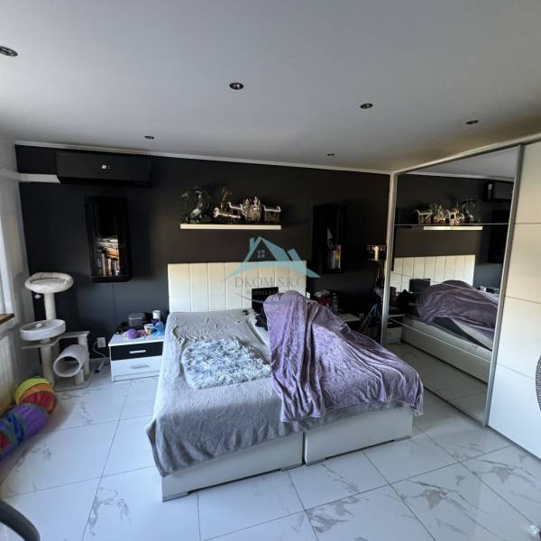 A bedroom in a two-room apartment with white furniture, decorations, and cat accessories.