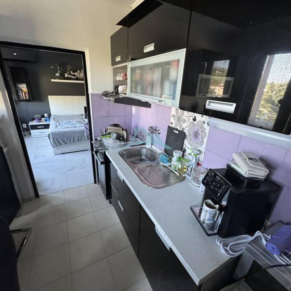 A kitchen with purple tiles and modern equipment in a 2-room apartment.