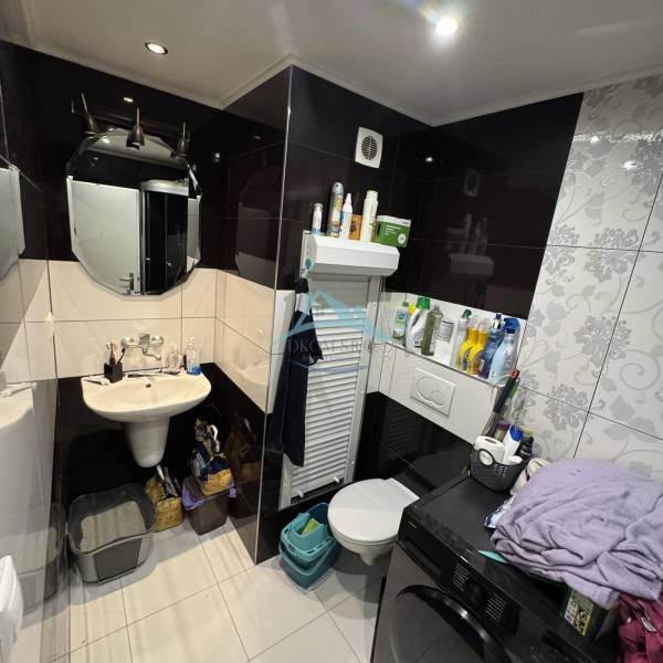 Bathroom in a 2-room apartment with a spacious toilet, sink, and washing machine.