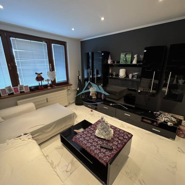 Living room in a two-room apartment with modern furniture and tiled flooring.
