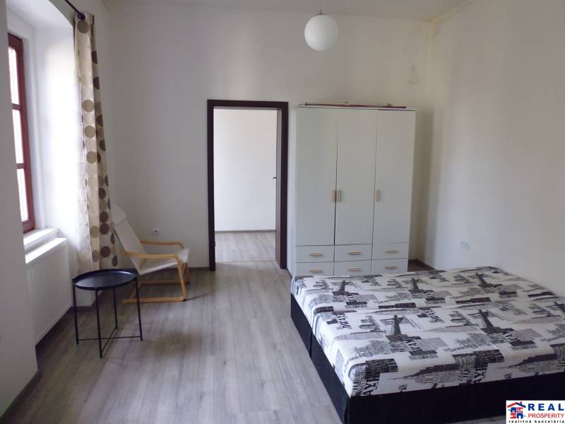 Bedroom in a 3-room apartment with wood-patterned flooring, a wardrobe, and a bed.