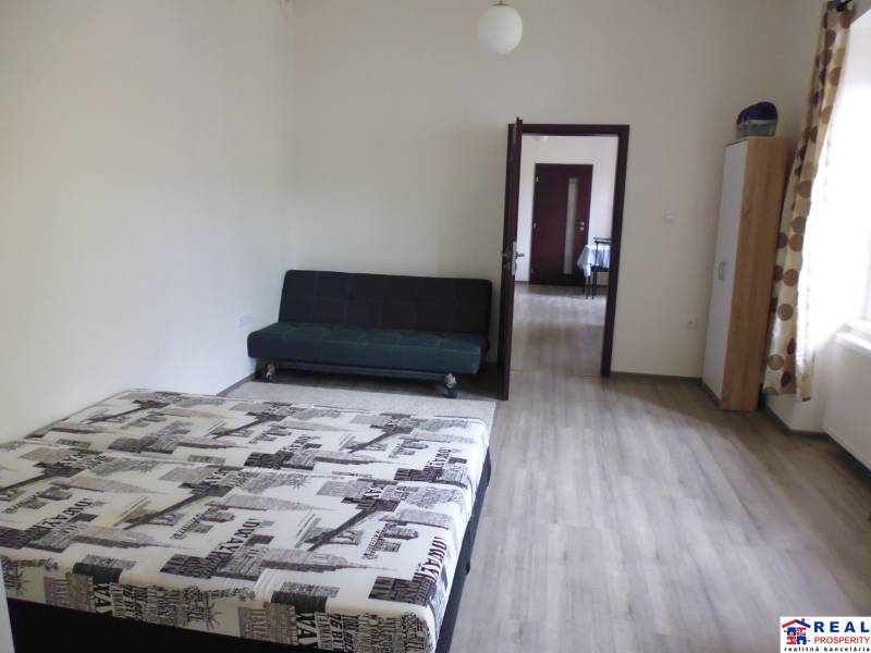 A bedroom in a 3-room apartment with a bed, sofa, and wooden decor flooring.