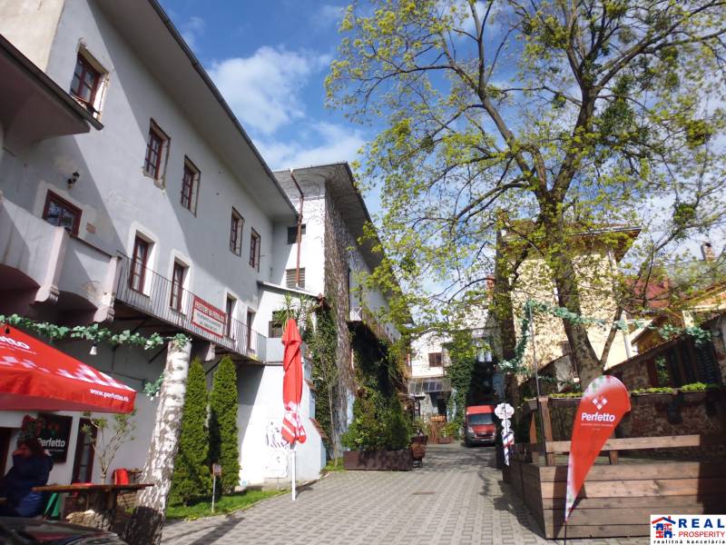 A narrow courtyard with three-story buildings and café chairs on Hlavná Street in Prešov.