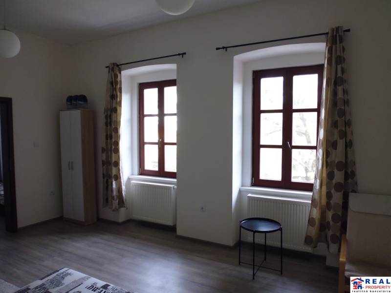 A room with large windows, curtains, and a wooden decor floor in a 3-room apartment.
