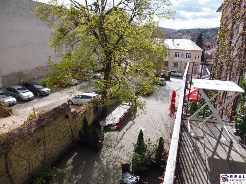 View from the balcony of a 3-room apartment on Hlavná Street in Prešov with a parking lot and greenery.