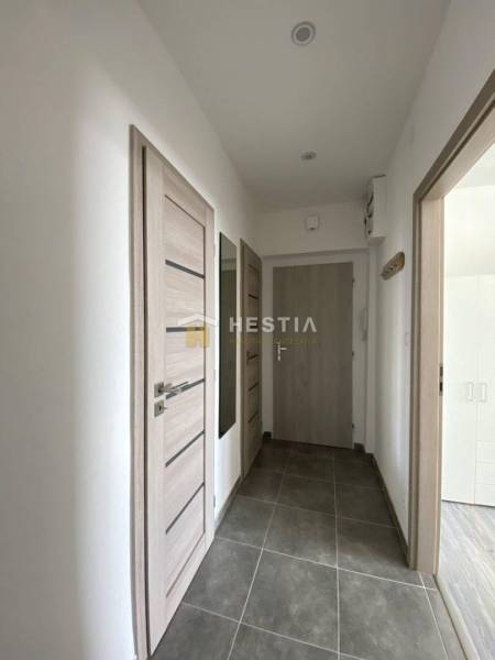 A hallway with light doors in a 2-room apartment, gray tiles on the floor.