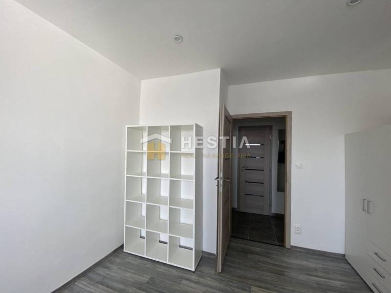 A room in a 2-room apartment with a shelving system and a floor with a wood decor.