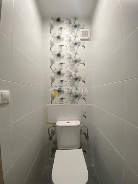 A toilet with patterned tiles in a 2-room apartment.