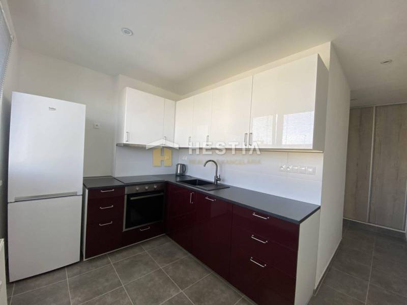 A kitchen in a 2-room apartment with dark cabinets and white appliances.
