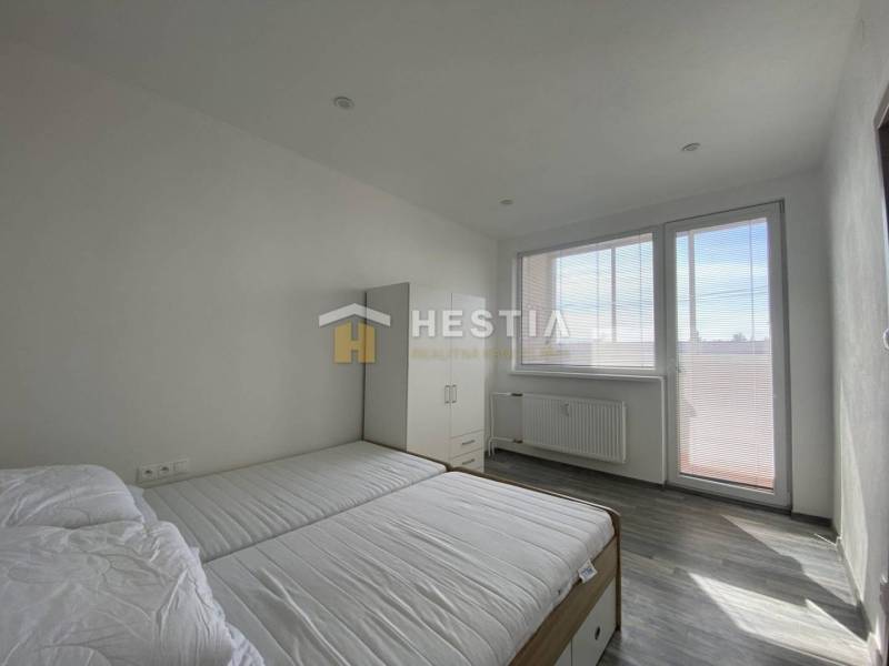 Bedroom with a bed, wardrobe, and large window in a two-room apartment.