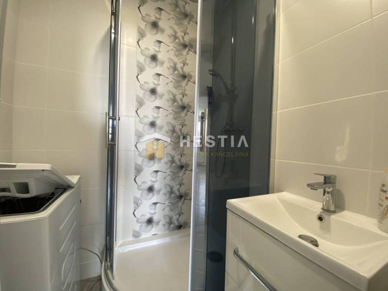 Bathroom in a 2-room apartment with a modern shower and a washing machine.