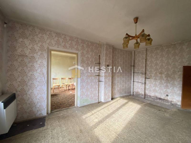 A room in a family house with floral wallpaper, carpeted floor, and a chandelier.
