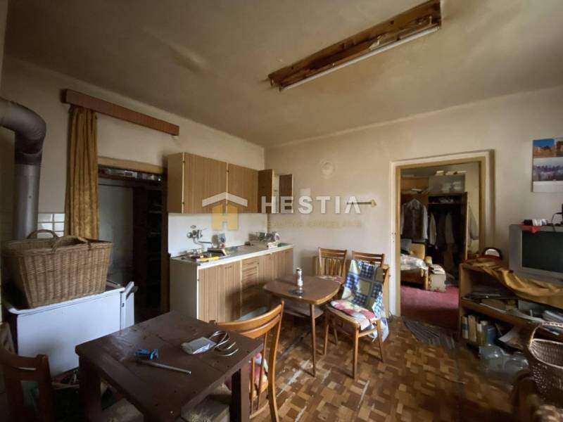 A kitchen in a family house with wooden furniture, an old television, a dining table, and a wardrobe.