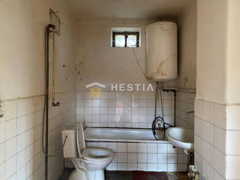 A bathroom in a family house with a bathtub, boiler, and toilet.