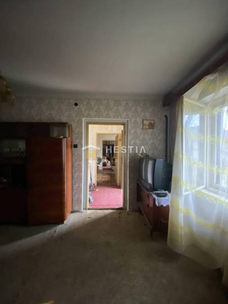 A room in a family house with retro furniture, an old television, a window with floral curtains.
