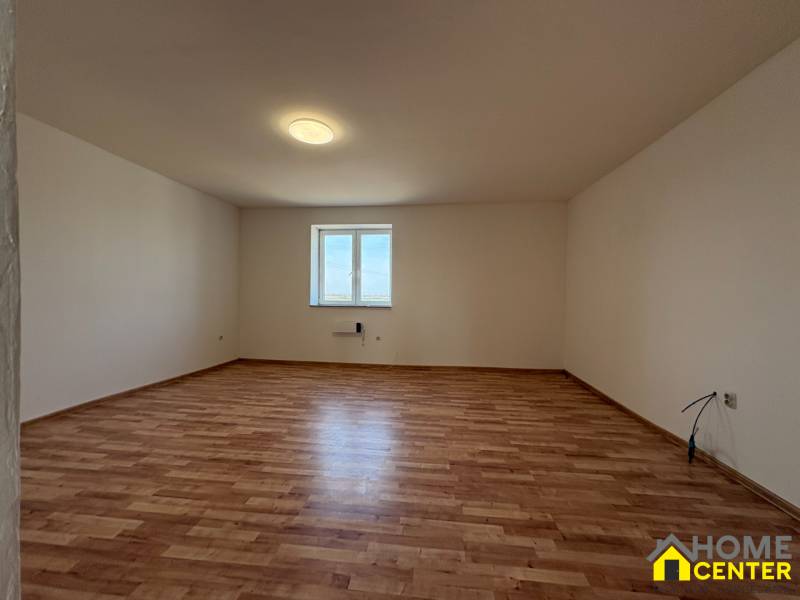 A spacious room with a window and a wooden decor floor in a family house.