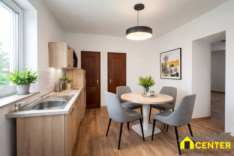 A kitchen in a family house with a wooden decor floor and a round table.