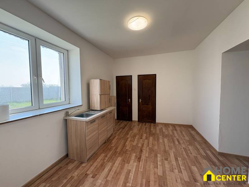 A room with a kitchen unit, a wooden decor floor, two wooden doors.
