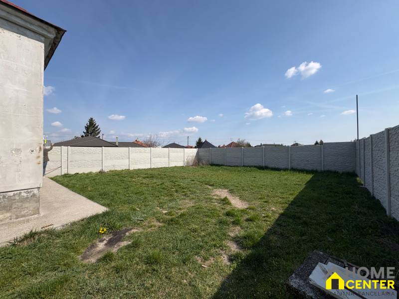 Garden at a family house in Zemianska Olča, surrounded by a fence, grassy surface.