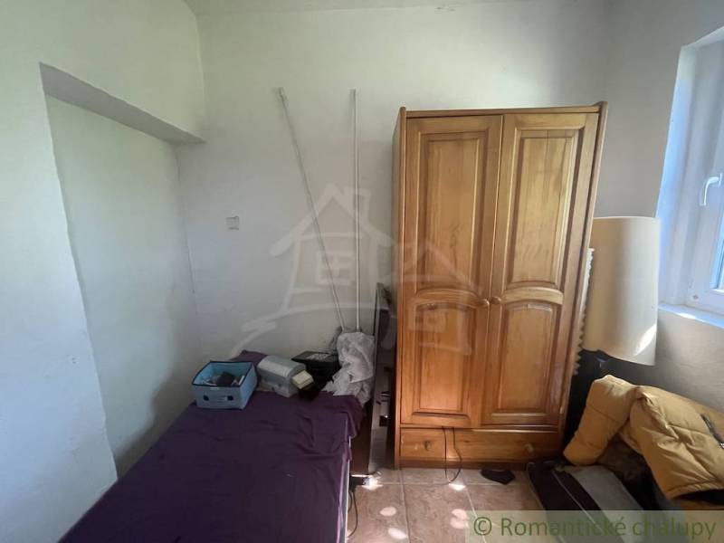A room in a family house with a bed, a wooden wardrobe, and a window.