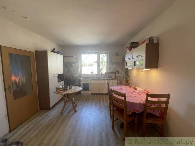 A kitchen in a family house with a wooden floor decor, simple furniture, and a dining table.