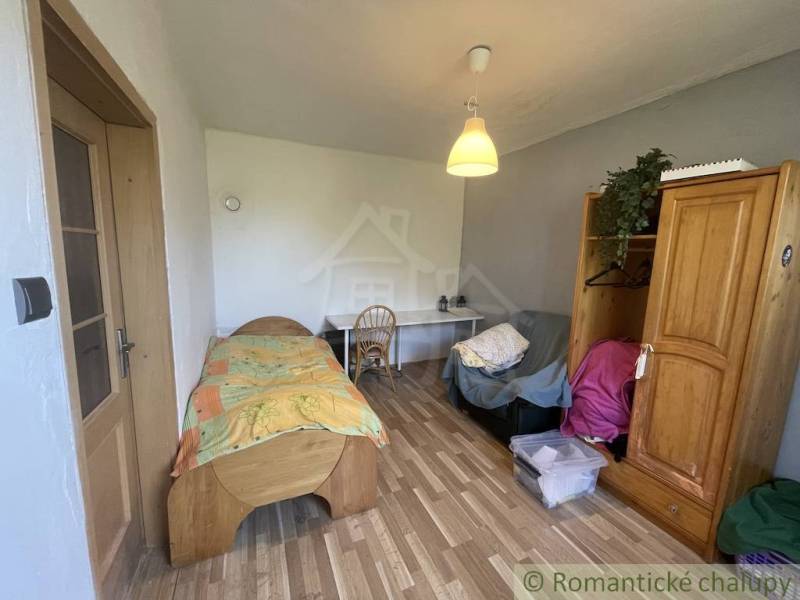 A room in a family house with a bed, a table, and a floor with a wooden decor.