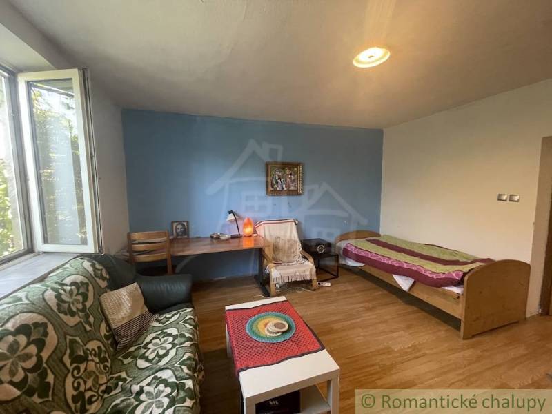 A room in a family house with a bed, a window, a sofa, and a floor with a wooden decor.