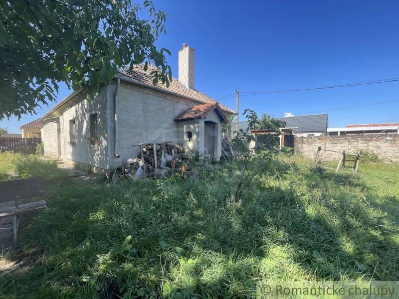 A family house in Jatov with a grassy yard and a pile of wood next to the house.