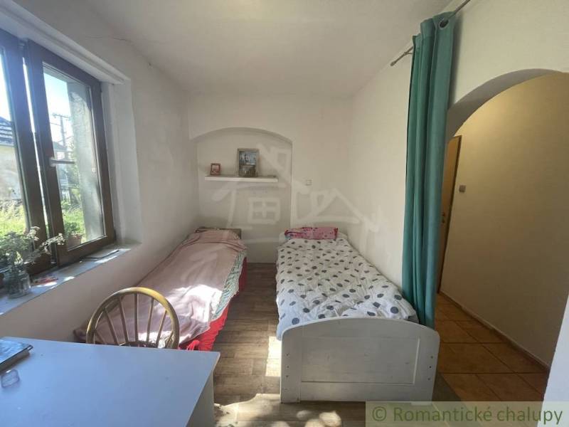 A room in a family house with two beds, a wooden-patterned floor, and a window.