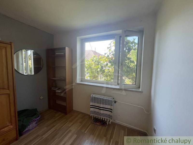 A room in a family house with a wooden decor floor, a window, and a shelf.