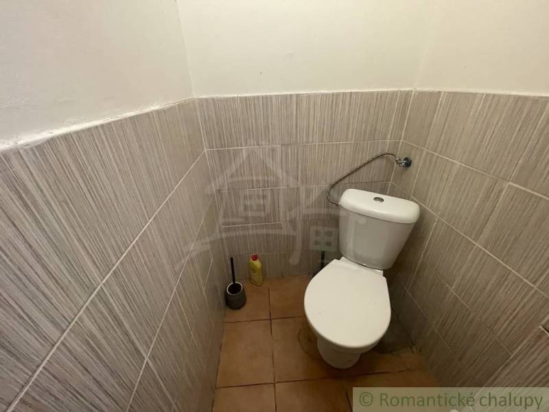 A toilet in a family house with ceramic flooring and tiles.