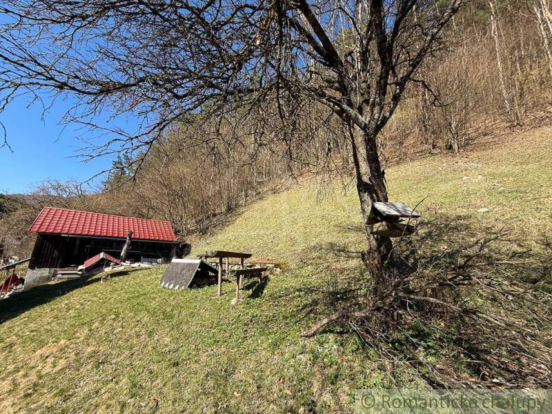 A cottage near Moštenica surrounded by trees and grassy hills under sunny weather.