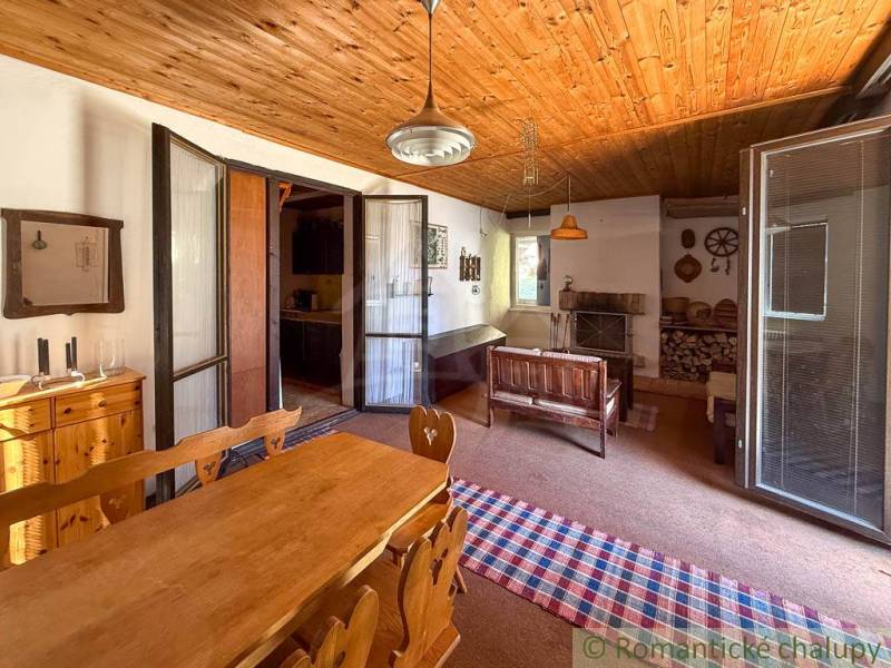 A kitchen in a cabin with a wooden ceiling and rustic furniture.