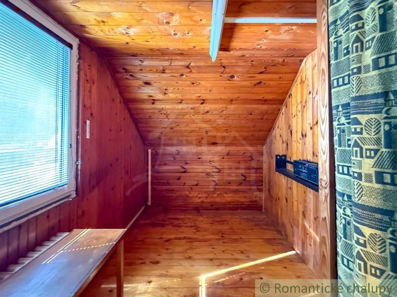 A room in a cabin with a wooden floor decor and a skylight.