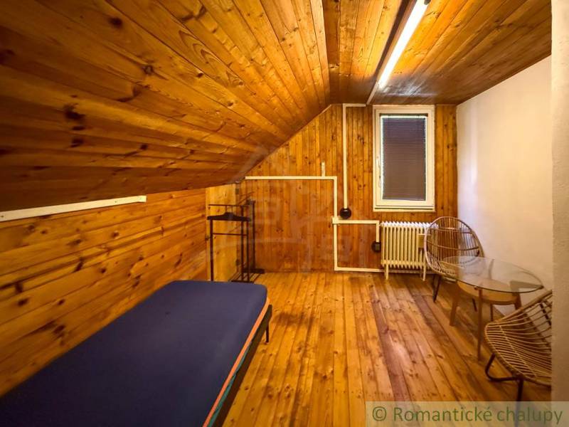 Interior of a cabin with a wooden decor floor, bed, and chairs for comfort.