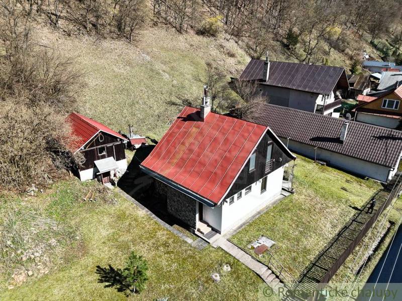 A cottage in Moštenica with a slanted red roof, surrounded by greenery and hilly terrain.